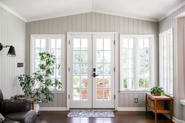 Organic modern entryway with matte black door hardware, indoor plant, and open sightline to an outdoor patio