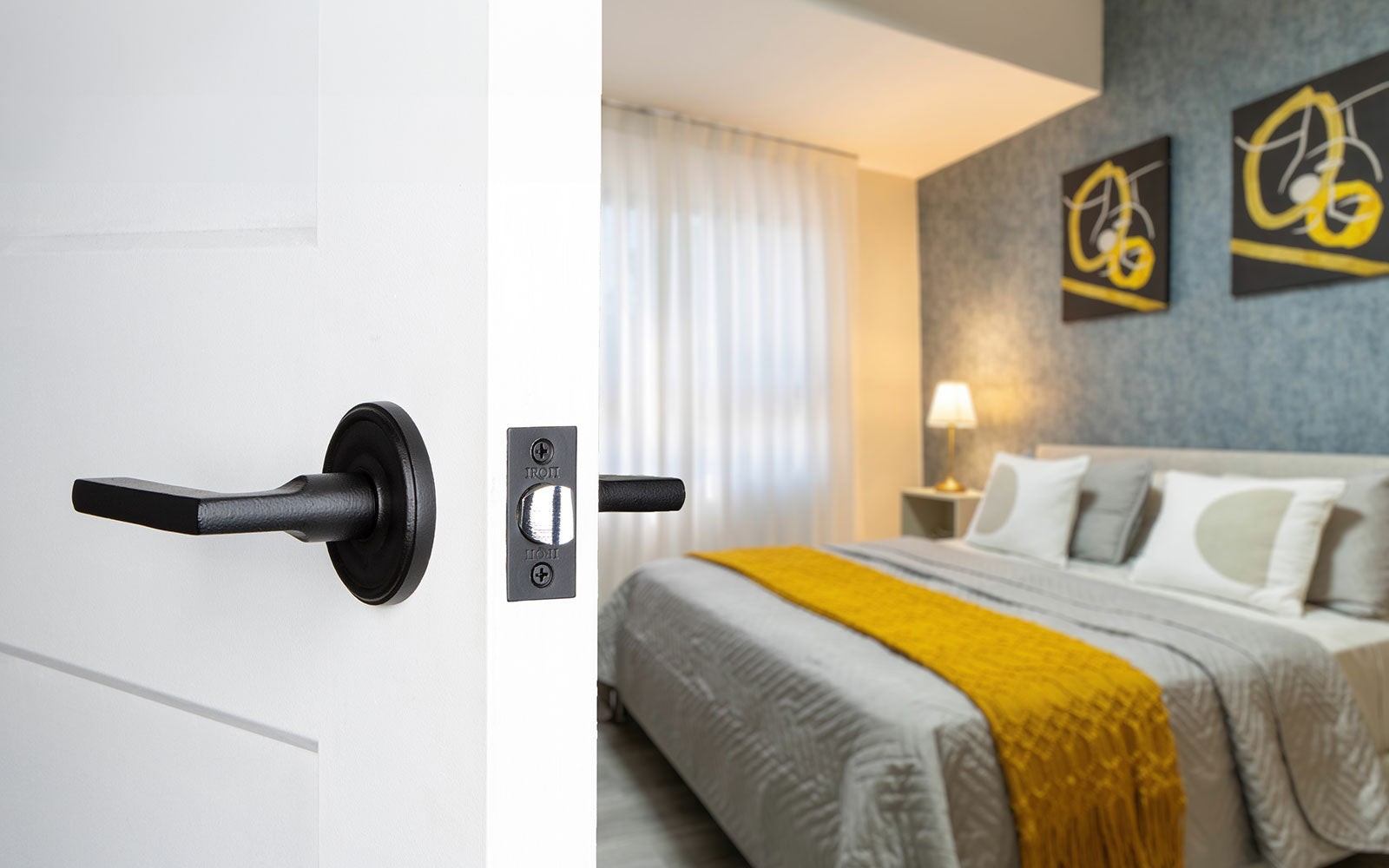 white door into a modern colorful bedroom with black iron door lever hardware from ageless iron
