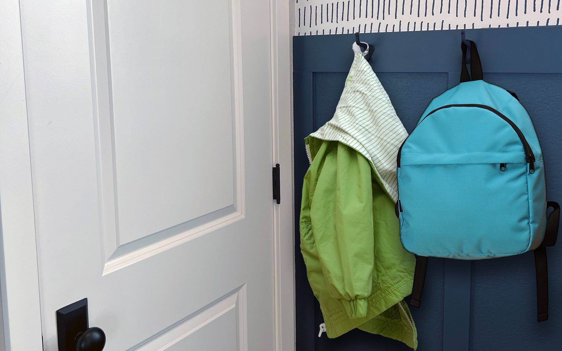 contemporary home with blue wall wainscoting organic wallpaper and black iron door hardware hinges and coat hooks